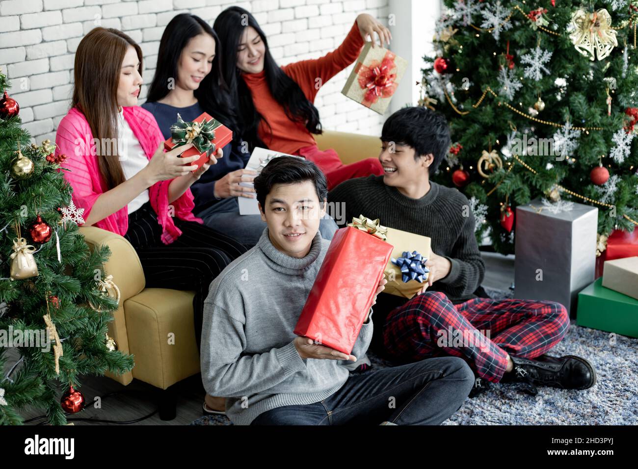 Happy of group young Asian with gifts at home in celebrating Christmas festival. Group of friends dressing up for Christmas party together. Celebratin Stock Photo