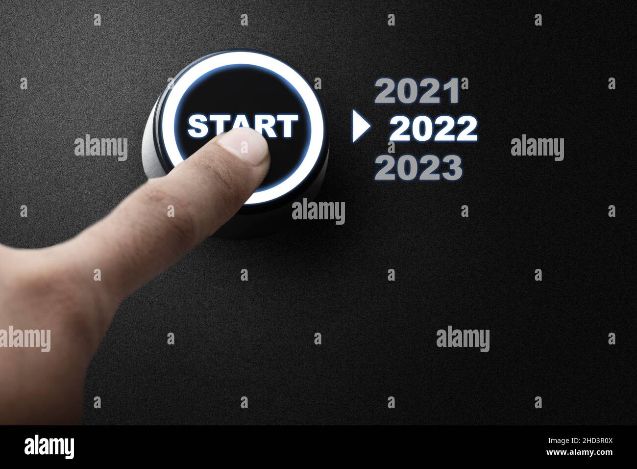 A human hand pushes the start button to start 2022. Happy New Year 2022