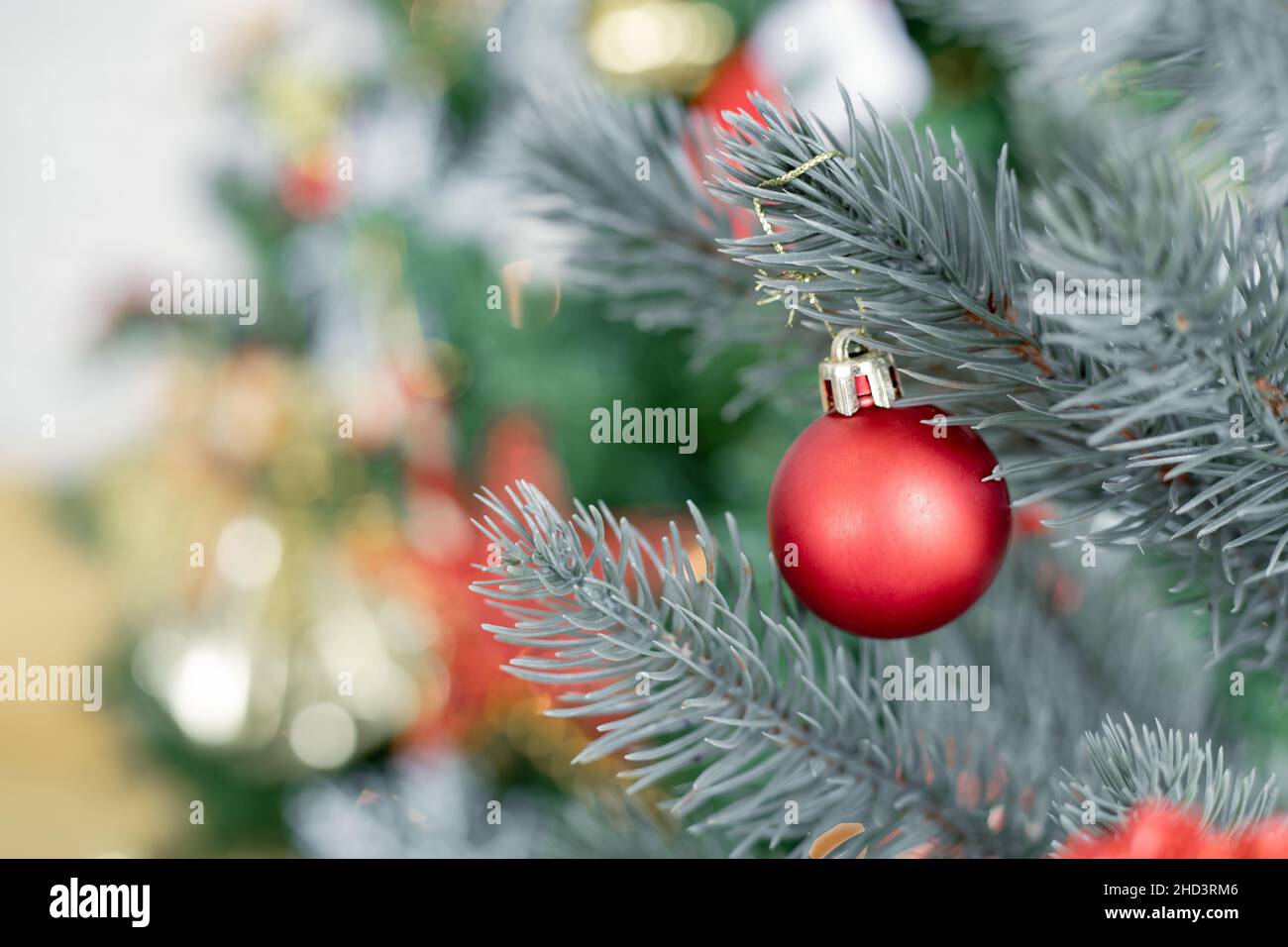 Closeup of red ball hanging from a decorated Christmas tree with copy space. Christmas and New year holidays background. Stock Photo