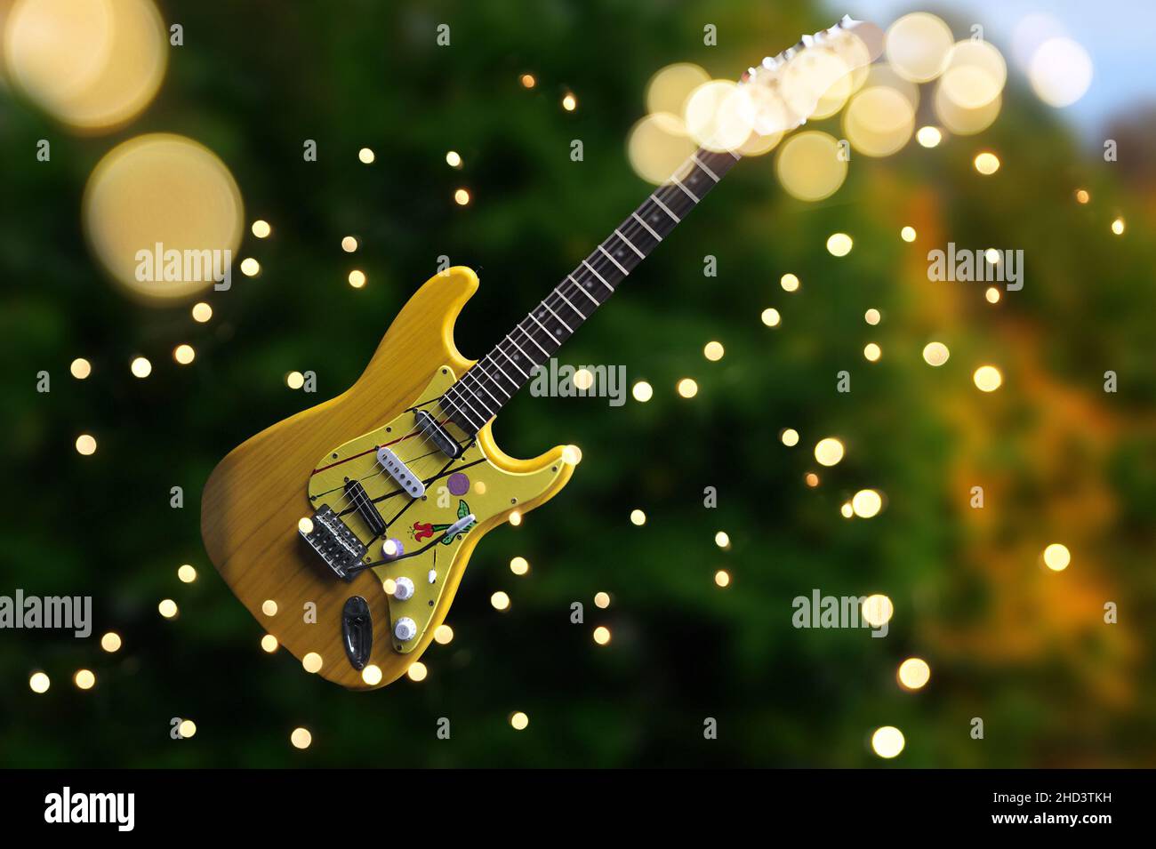 Yellow guitar floating in the air against greein background with