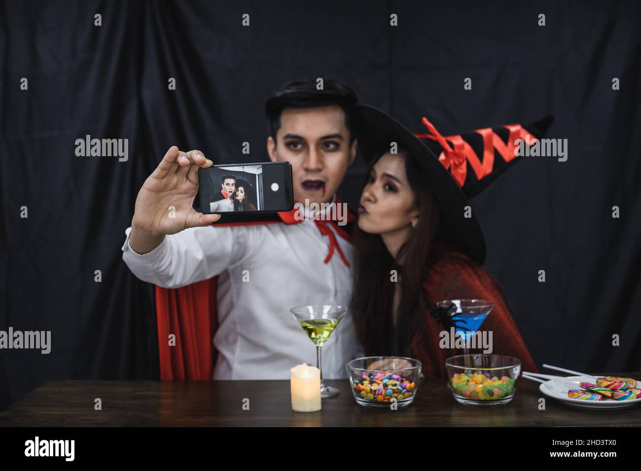 Young Asian couple in costume witch and dracula with selfie by mobile in celebrate party Halloween festival. Couple in costume celebrate Halloween par Stock Photo