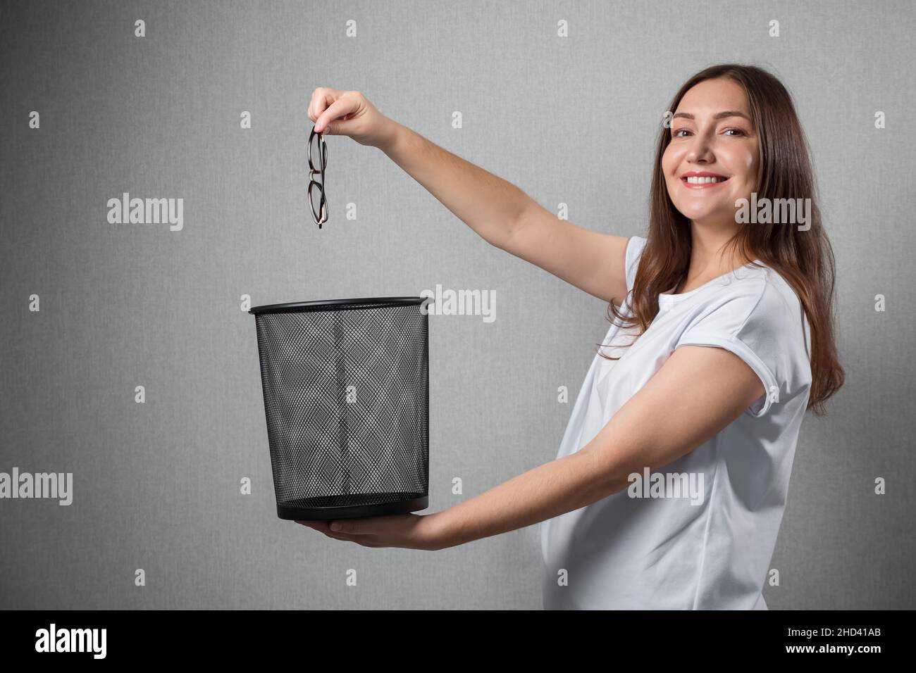 Happy woman throws away eyesight glasses into trash bin Stock Photo Alamy