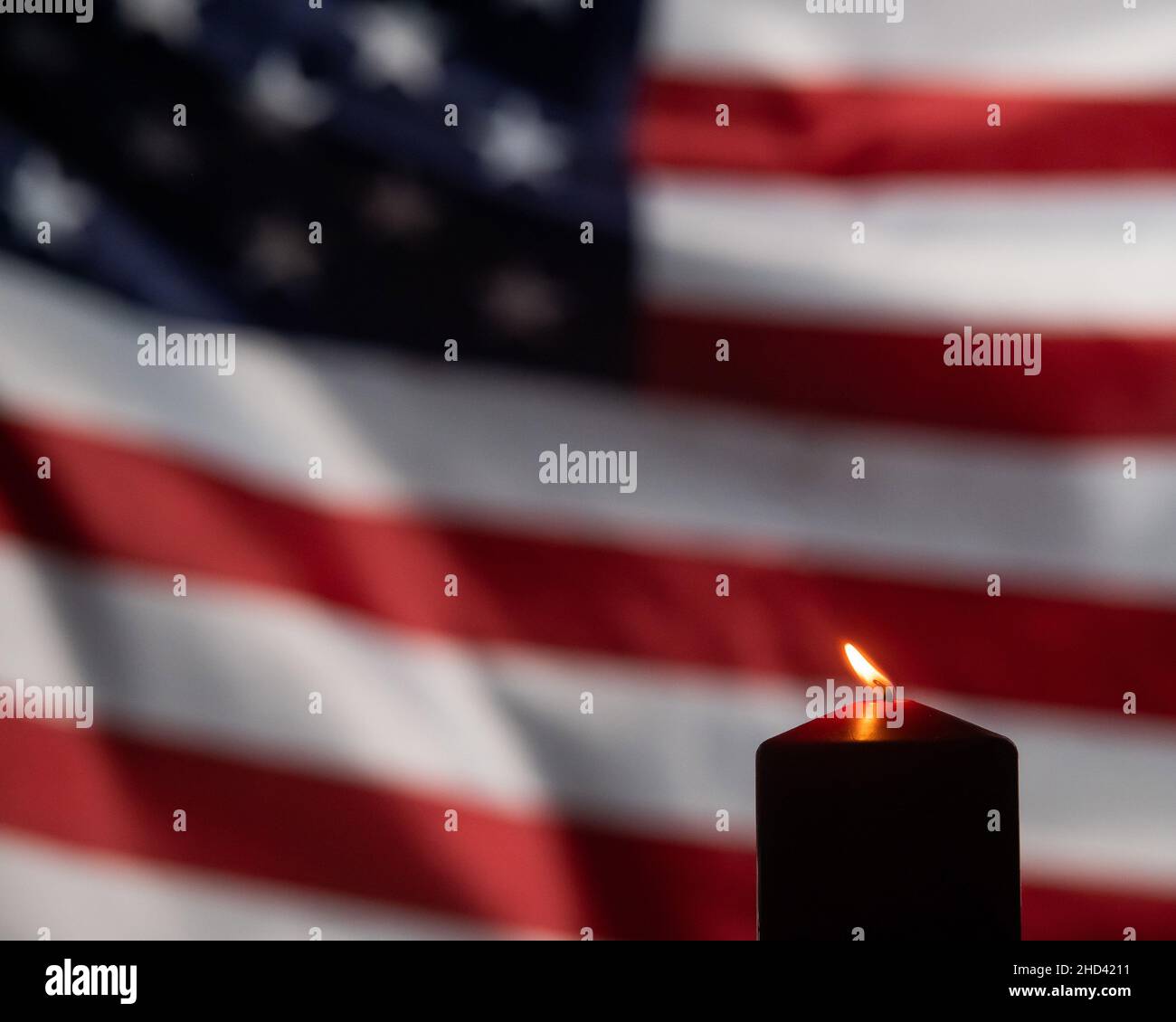 Burning candle against the background of the waving flag of the united