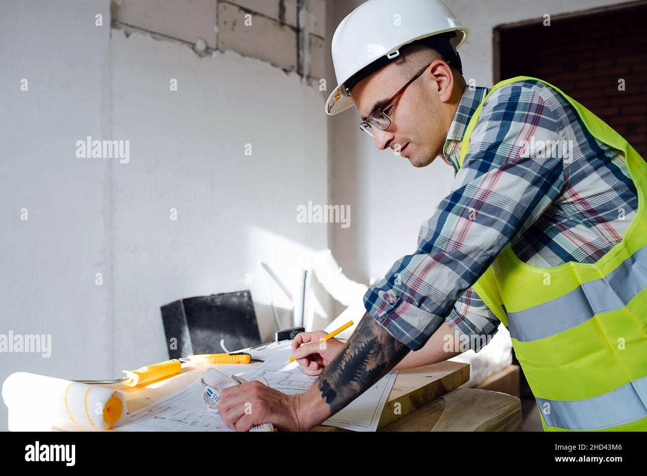 Engineer Side View Side view of a thoughtful construction engineer in white helmet drawing ...