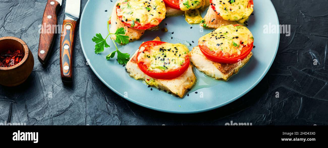 Slice of fish baked with cheese,tomato and herbs.Roasted pangasius Stock Photo