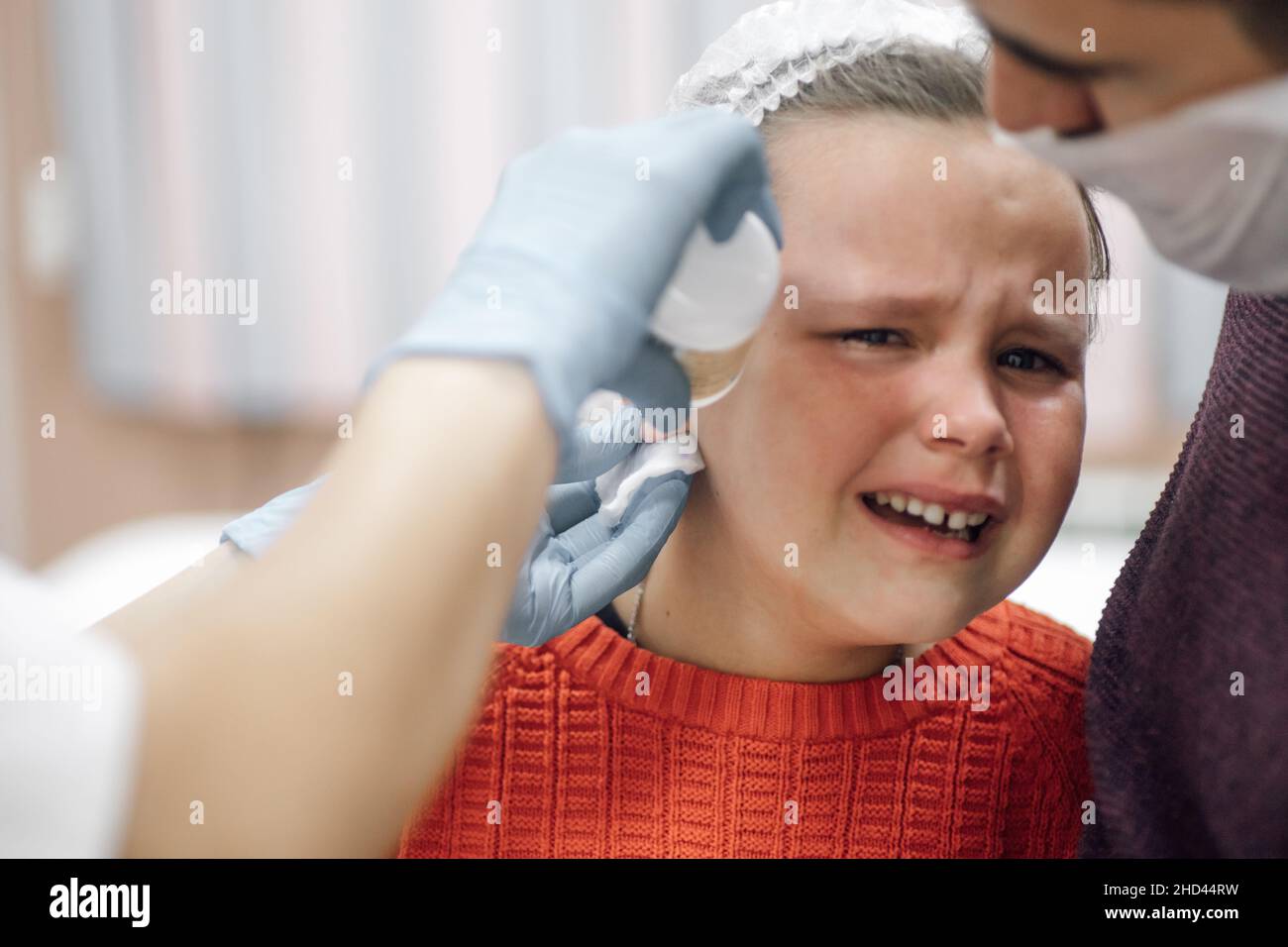 Nurse in disposable medical gloves treat and disinfect the ear puncture