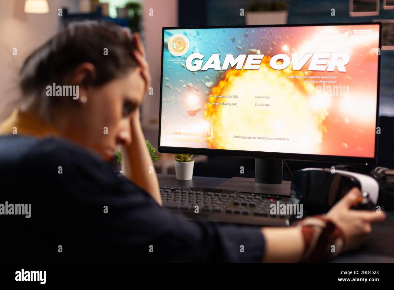 Frustrated woman losing online video games on computer. Disappointed person playing on monitor, using controller and feeling sad about lost game. Gamer with electronic e sport. Stock Photo