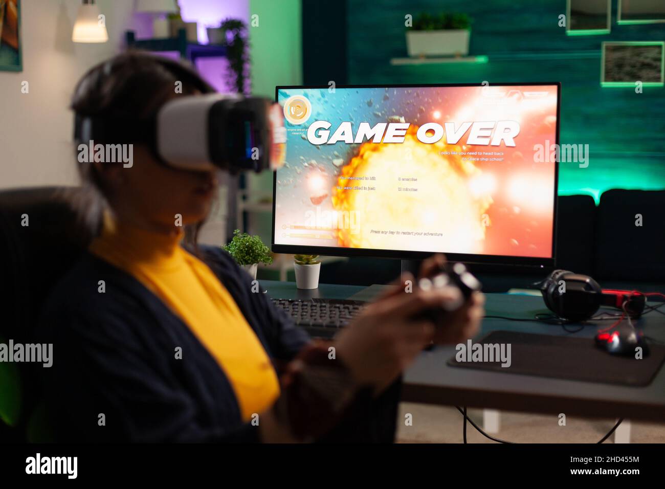 Adult with vr glasses losing video games on monitor. Woman playing game with controller and virtual reality headset on computer. Person lost online game with goggles and joystick. Stock Photo