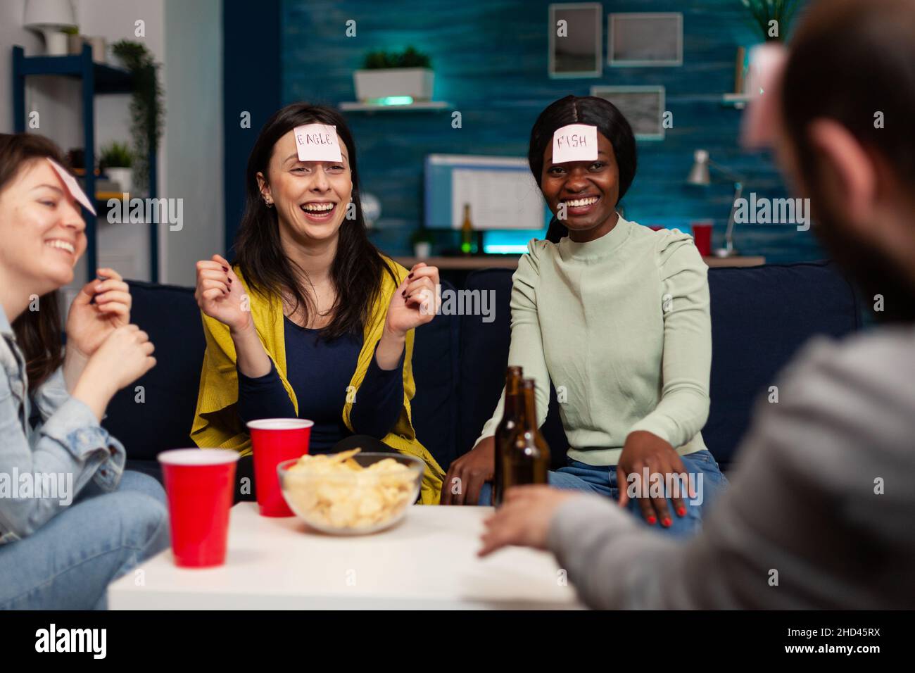 Laughing group of friends playing gusess game using stickey notes