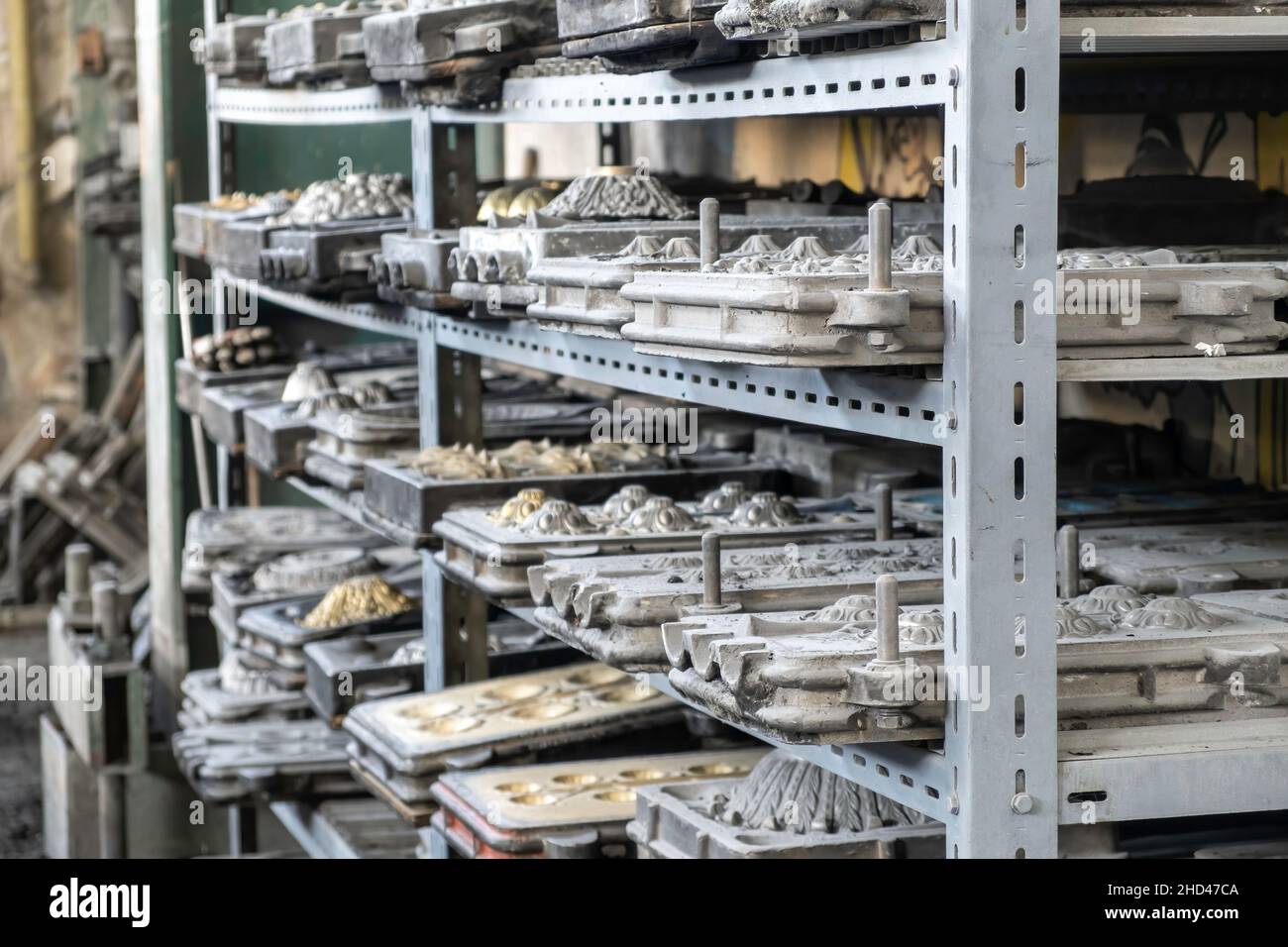 Metal molds for the production of various shapes of glass products lie on the shelves in the factory or glass manufacture. Stock Photo