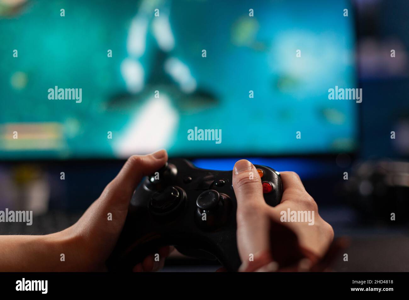 Close up of gamer holding controller and playing video games on computer.  Woman using joystick to play online digital games in front of monitor.  Person with modern gaming equipment Stock Photo 