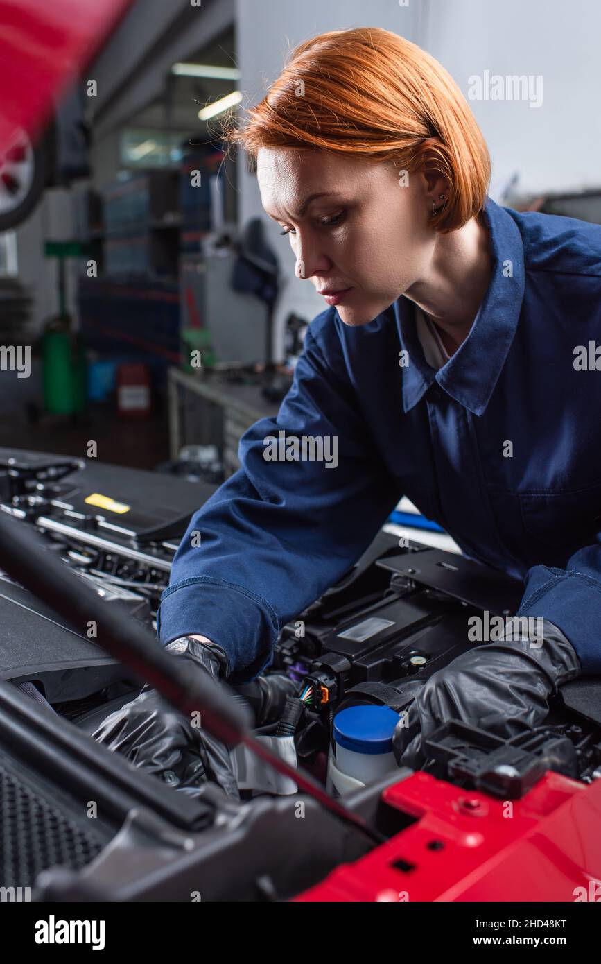 forewoman in uniform fixing motor of car in workshop Stock Photo