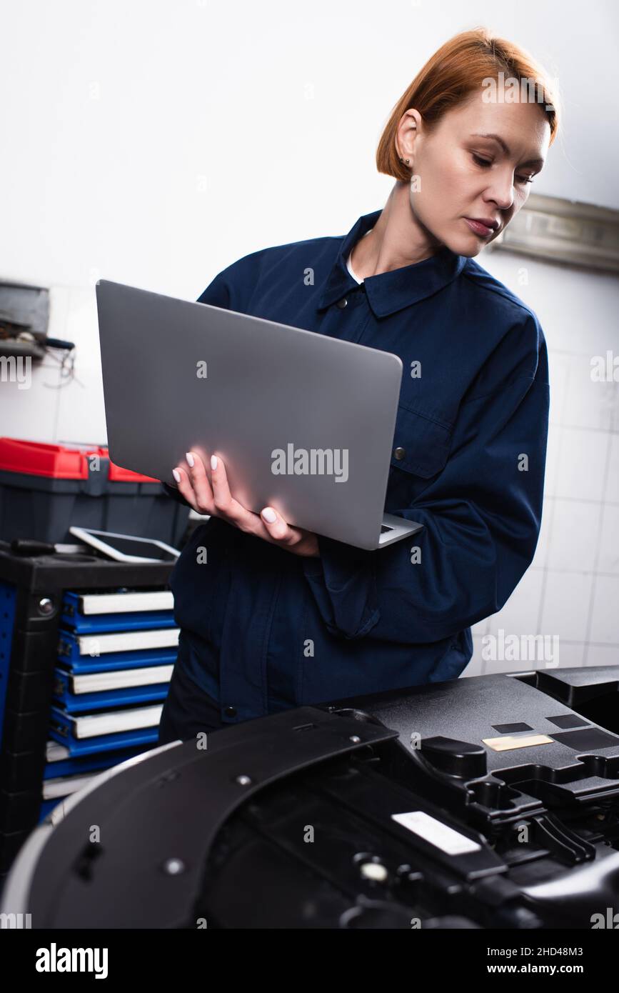 forewoman with laptop making diagnostics of car in workshop Stock Photo