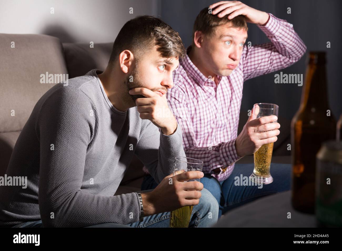 Upset male friends watching tv Stock Photo - Alamy