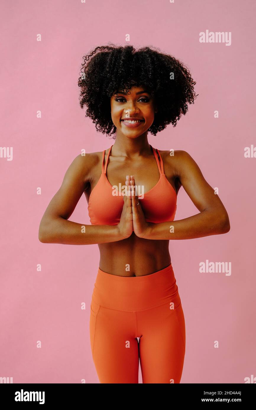 beautiful African american woman meditating in sports outfit on pink background Stock Photo
