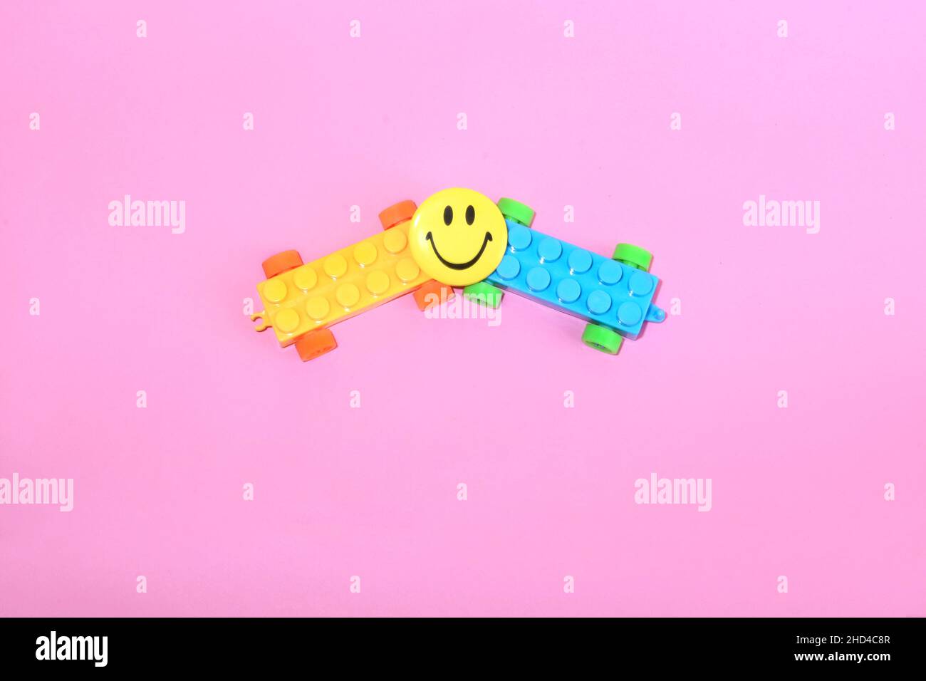 Top view of legos and a smiley face on a pink background Stock Photo