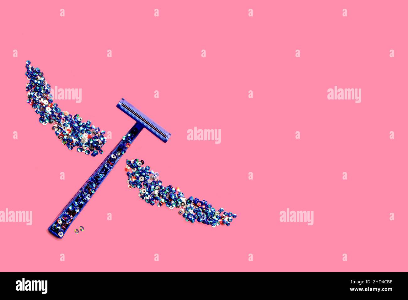Razor blade and a pair of wings made of sparkling little dazzles on a pink background Stock Photo