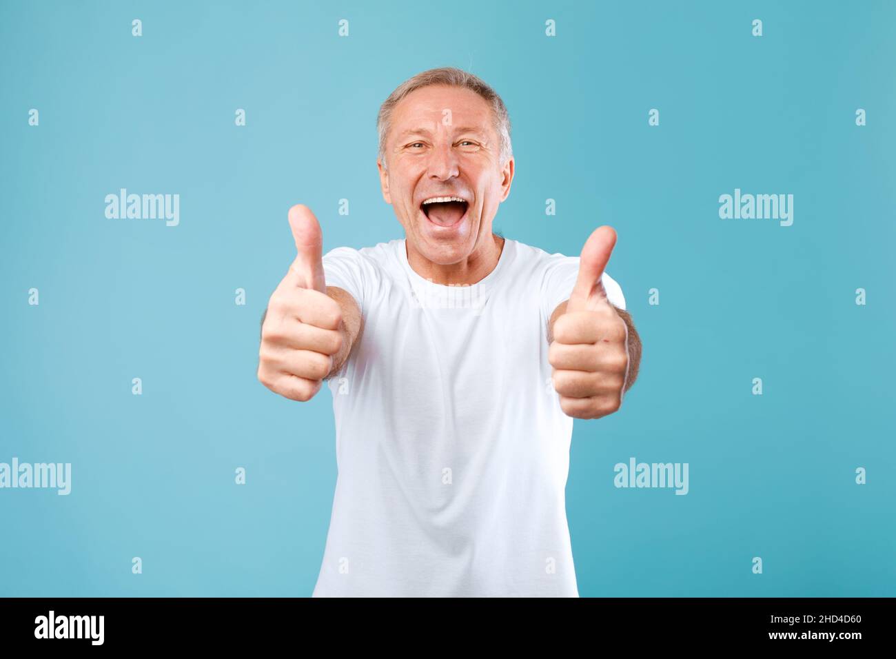 Excited mature man gesturing thumbs up and smiling Stock Photo