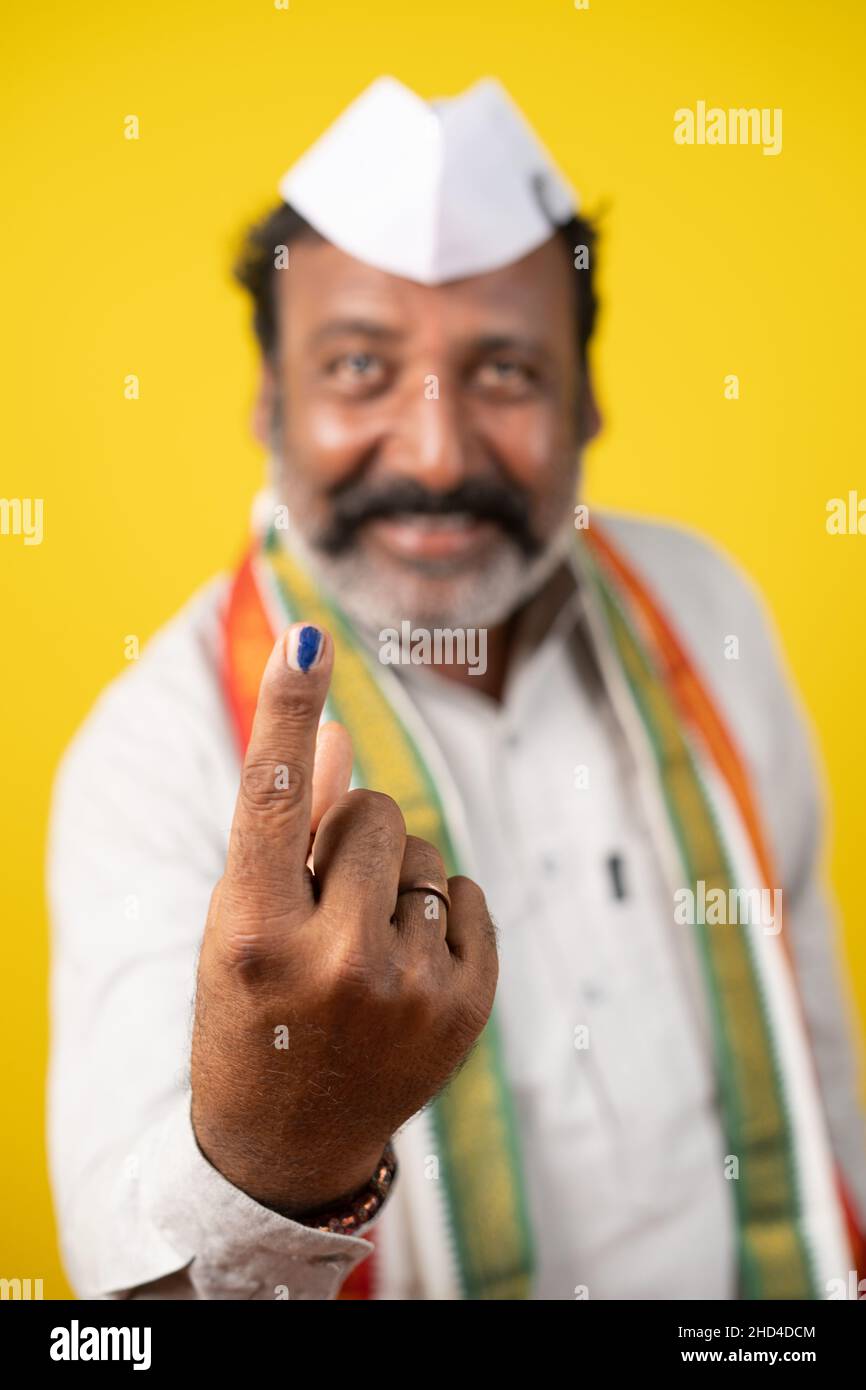 Selective focus on hand, portrait shot of Happy smiling politician showing ink marked finger after voting in election polls - concept showing of Stock Photo