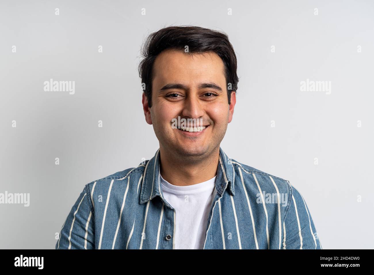 Brown skinned young adult man smiling at camera on isolated white background. Stock Photo