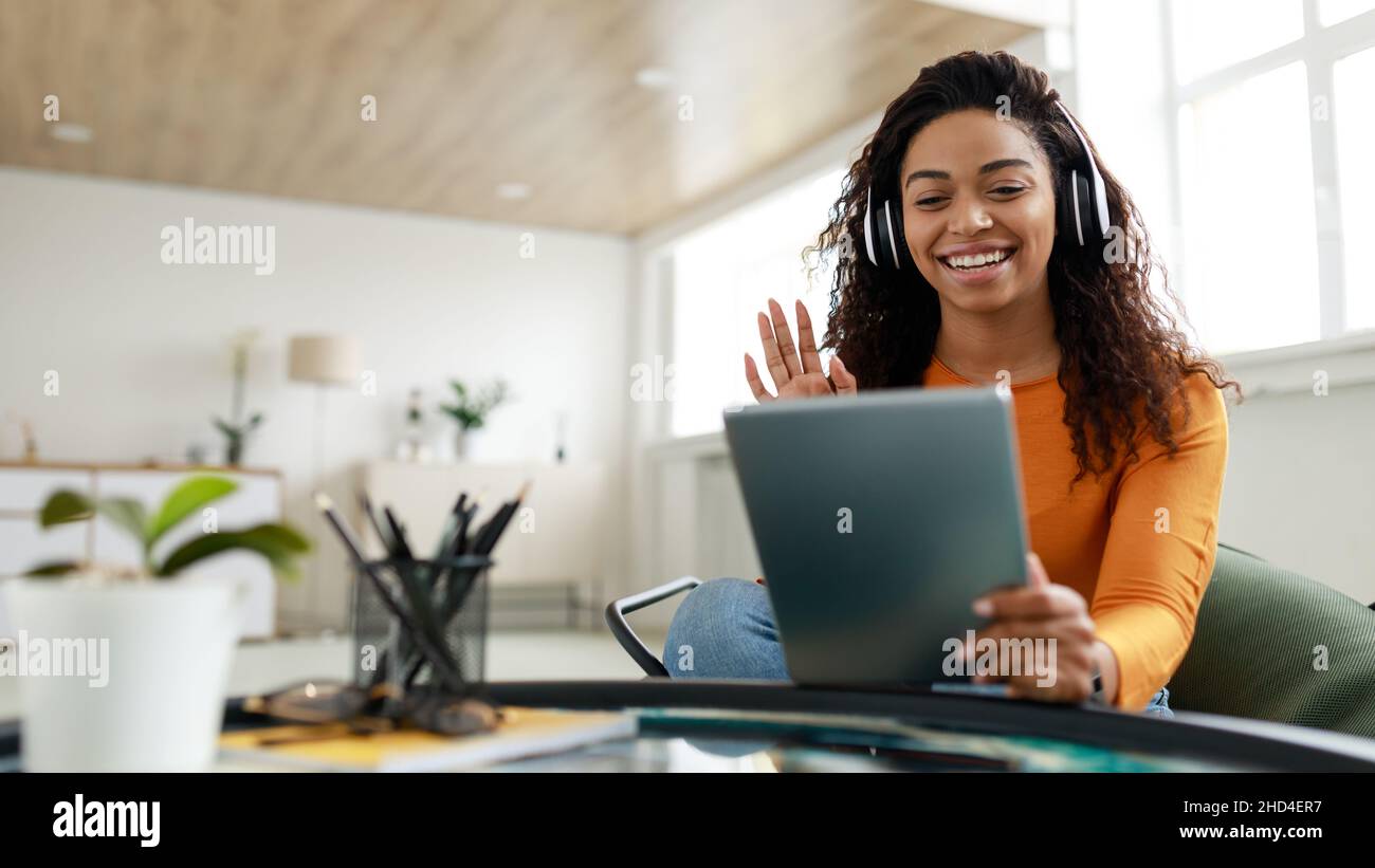 Black woman having video call using tablet and waving hand Stock Photo ...