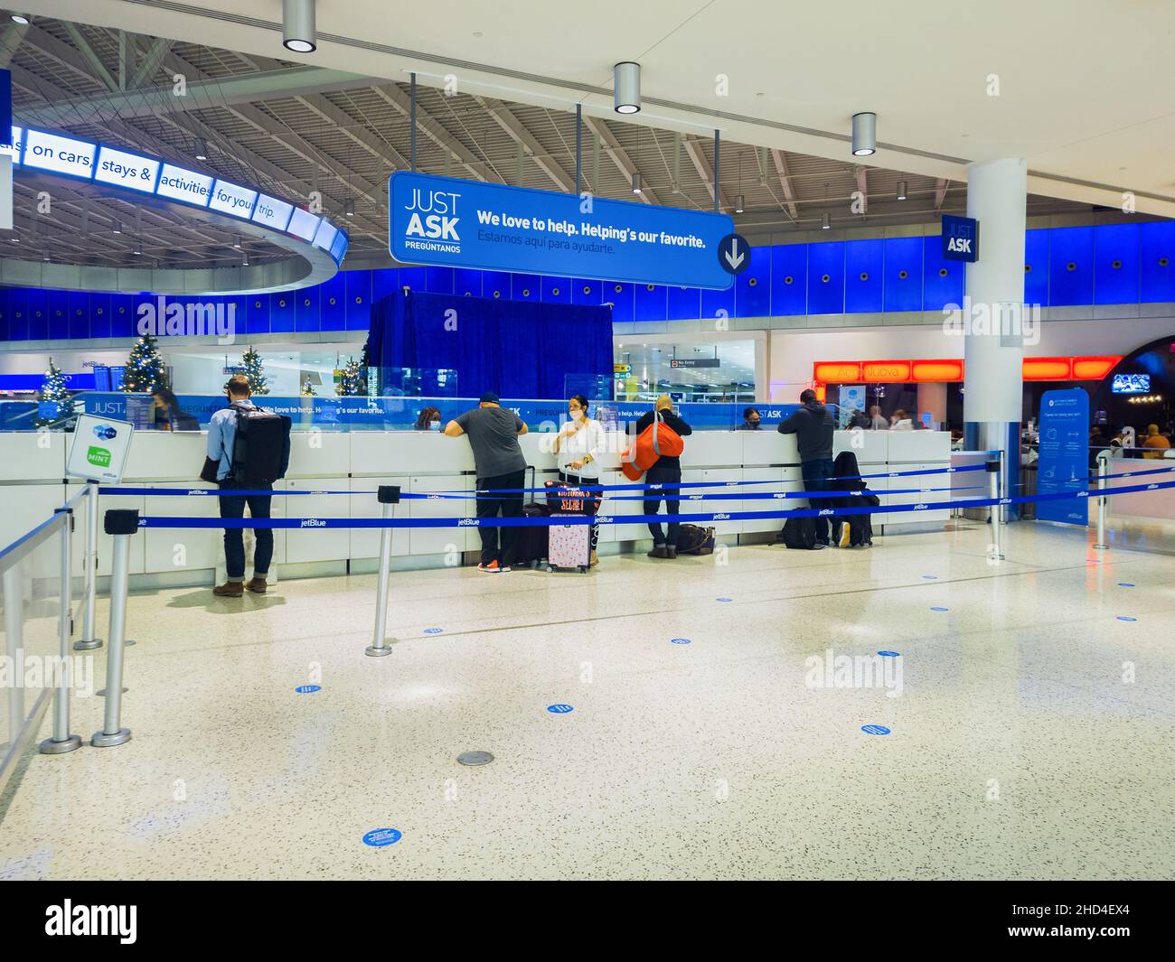 New York, USA - December 25, 2021: Horizontal View of the Information Help Desk of Terminal 5 of John F. Kennedy Airport with Travelers Being Helped. Stock Photo