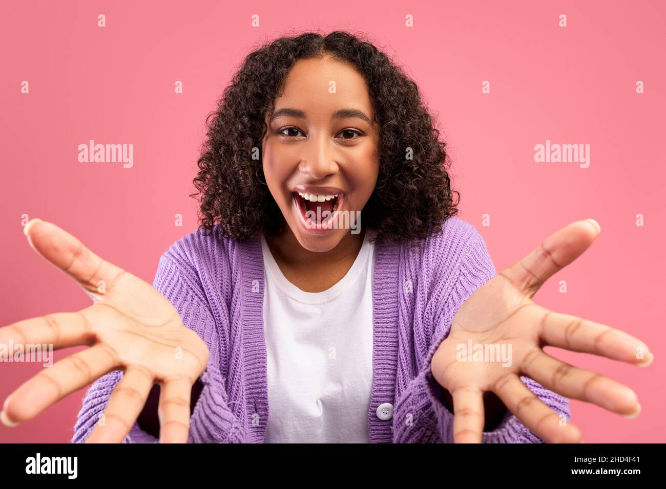 Emotional young African American woman gesturing hands at camera, shouting OMG, celebrating big win on pink background Stock Photo