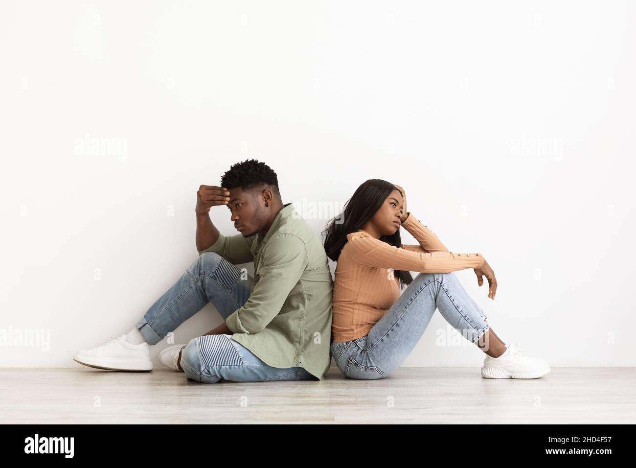 Upset african american couple sitting back to back on floor Stock Photo ...