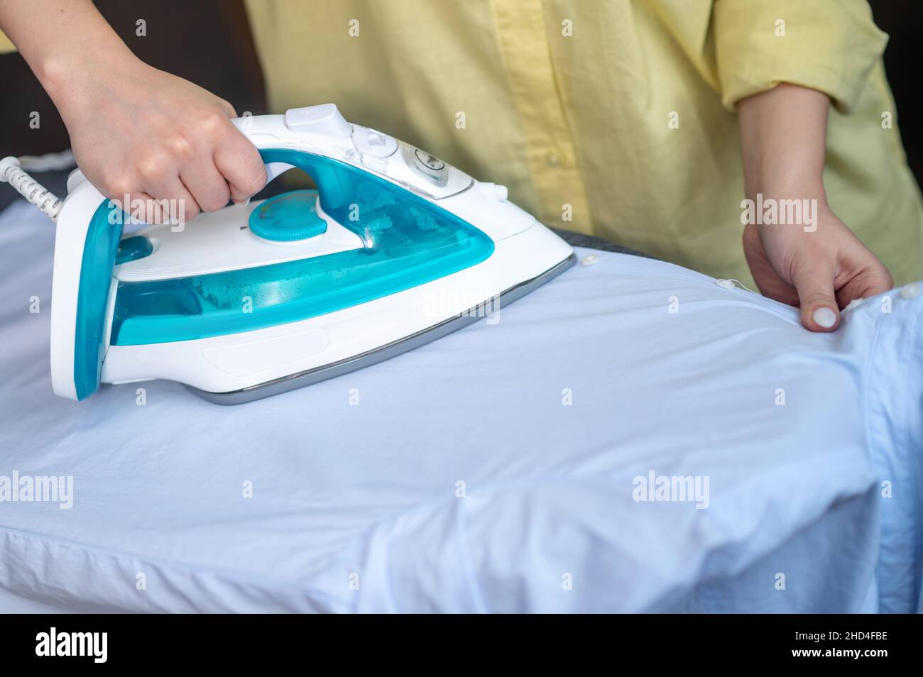 Female smoothing out wrinkles on the washed shirt Stock Photo