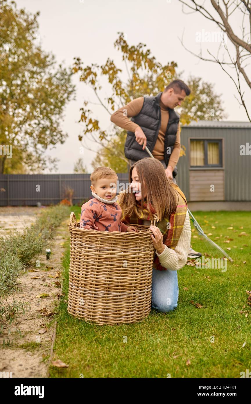 Joyful woman crouching looking at child in basket outdoors Stock Photo