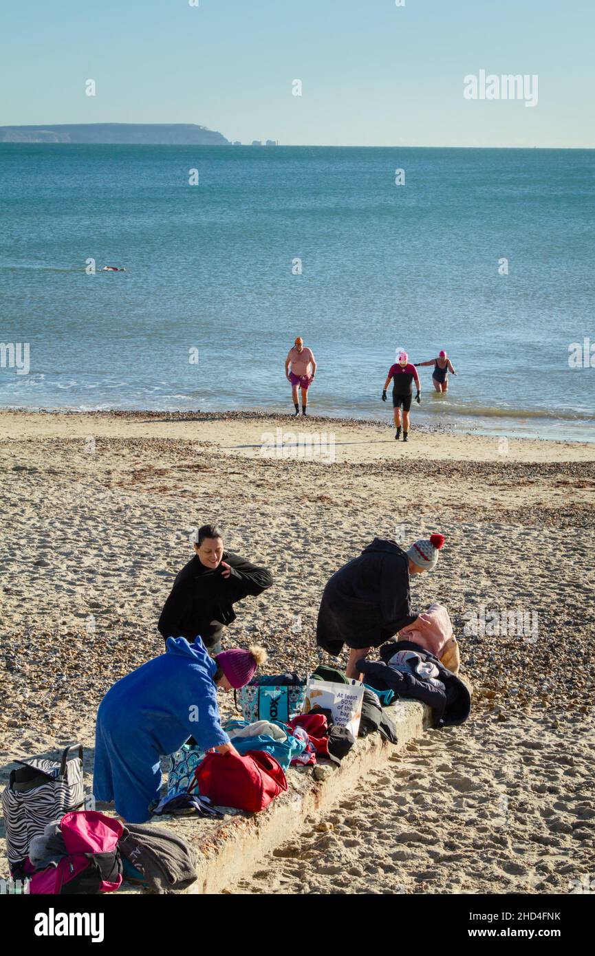 Group Of Wild Swimmers Changing And Leaving The Sea At Avon Beach Christchurch UK With View Of Solent Towards Needles And The Isle Of Wight UK Stock Photo