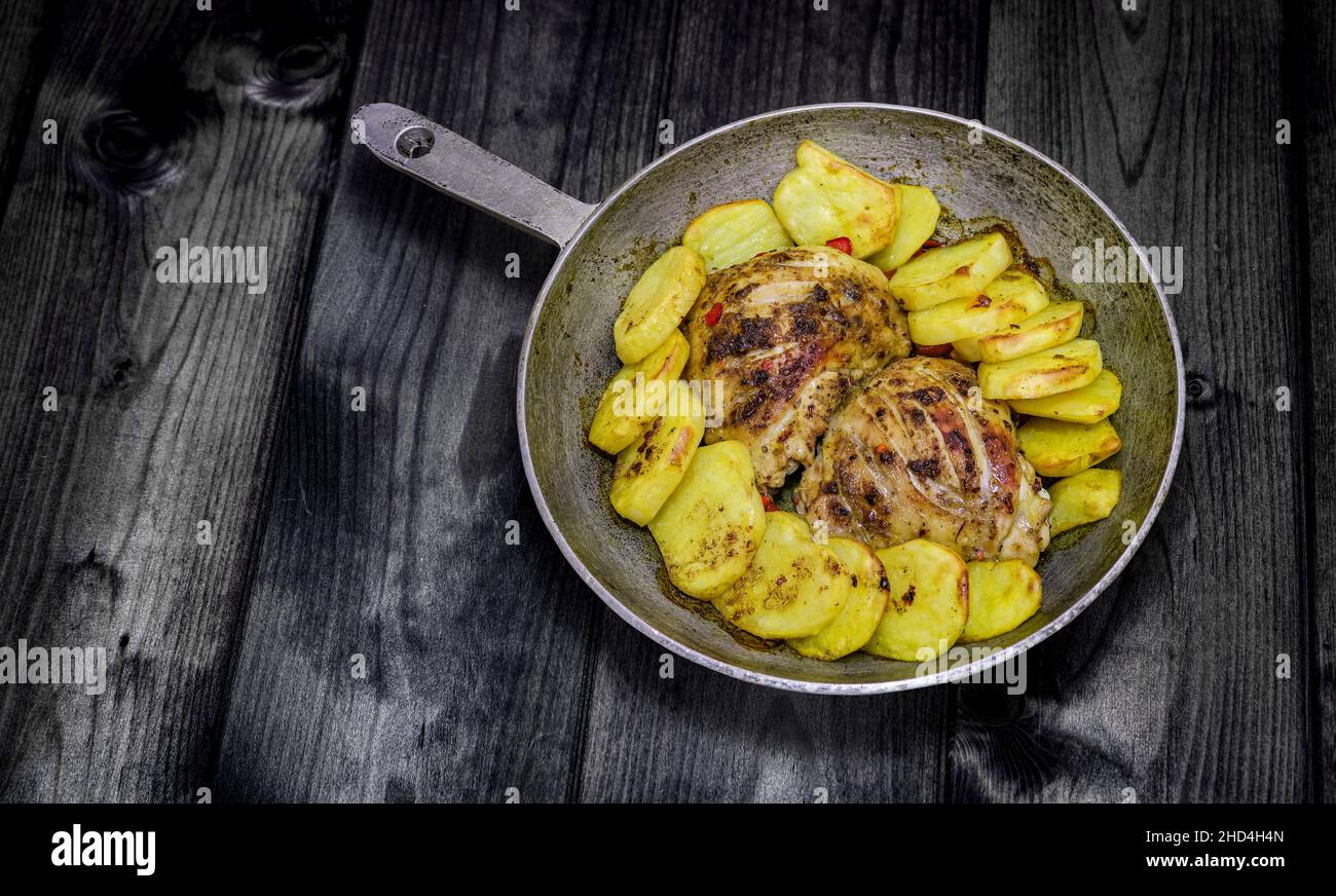Vintage photo - old pan with baked chicken and potatoes. Brutal menu. Copy space. Stock Photo