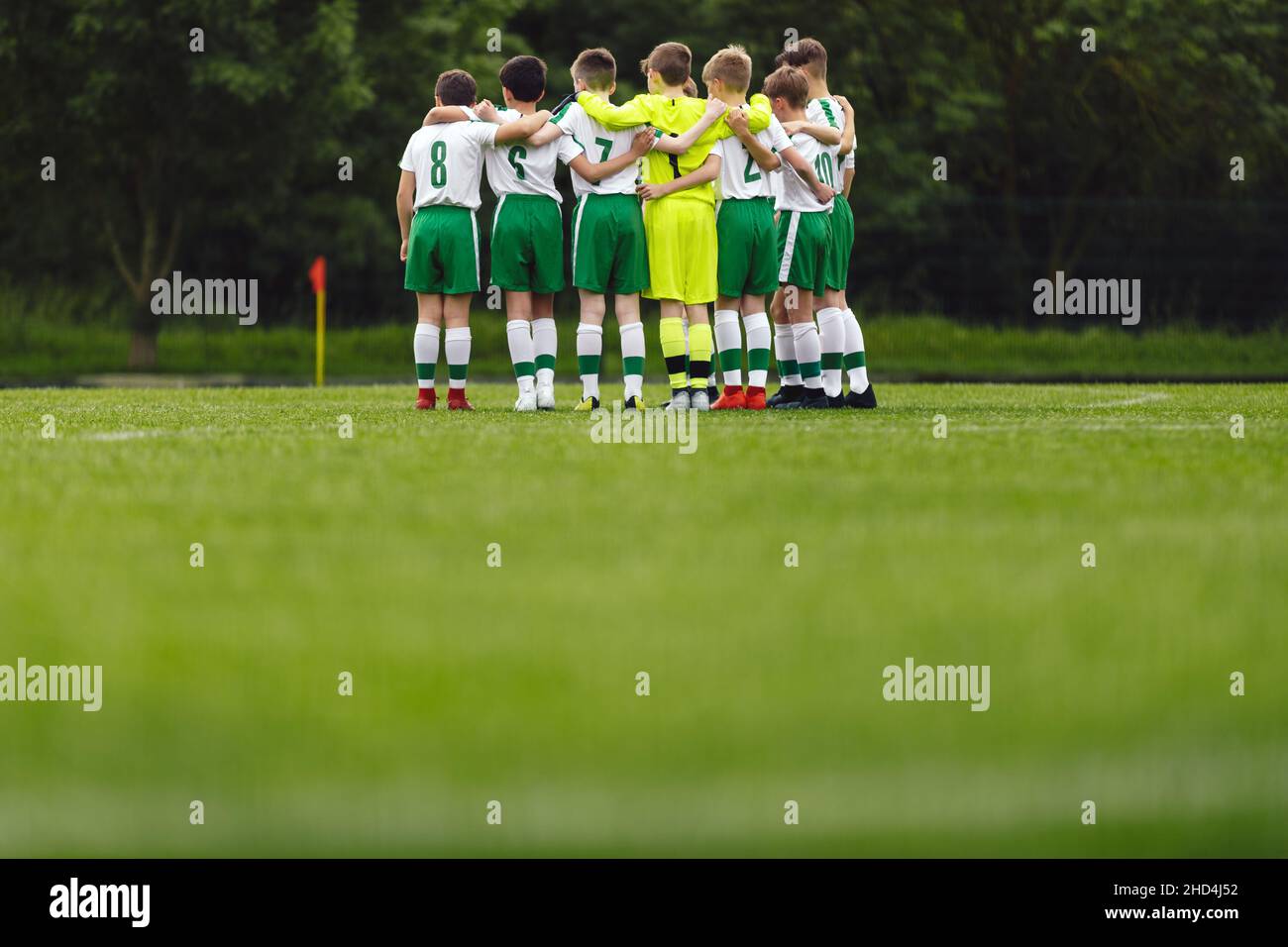 Soccer huddle. School boys standing together united in a team. Elementart age kids in sport team standing in circle on grass field Stock Photo