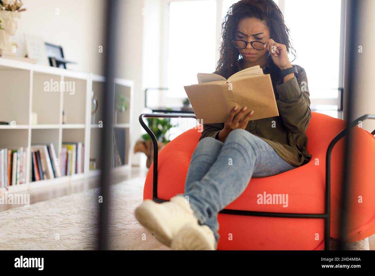 Focused black woman in glasses trying to read book Stock Photo