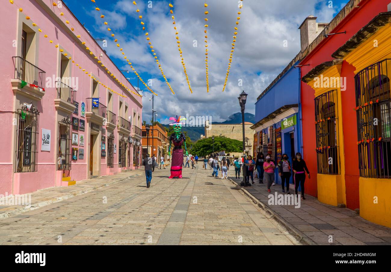 People walking by colonial houses and day of the Dead sculpture in Oaxaca, Mexico Stock Photo