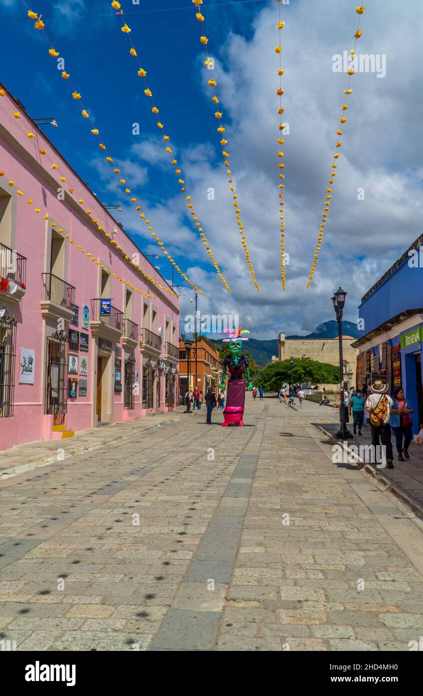 People walking by colonial houses and day of the Dead sculpture in Oaxaca, Mexico Stock Photo