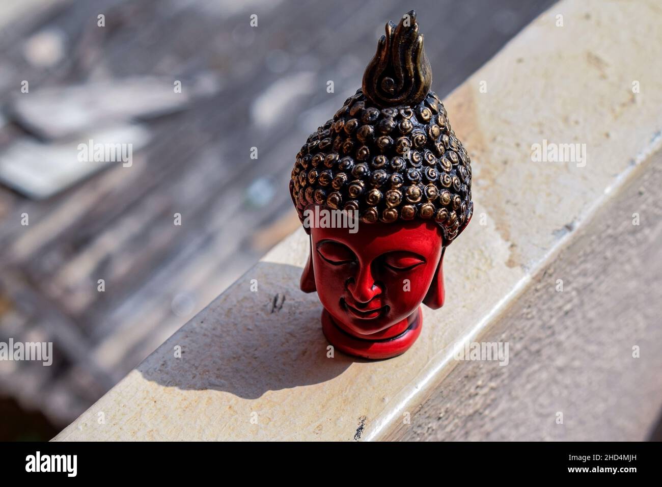 Stock photo of beautiful red color face sculpture or statue of lord buddha, head of statue painted with black and golden color on blur background ,Pic Stock Photo