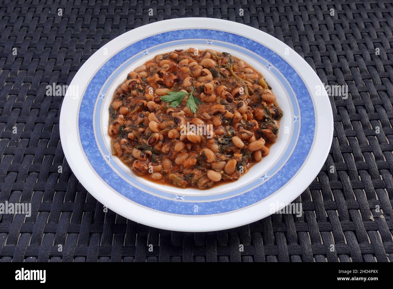 Black eyed peas with tomato sauce spinach and other vegetables. Mavromatika fasolia greek food. Stock Photo