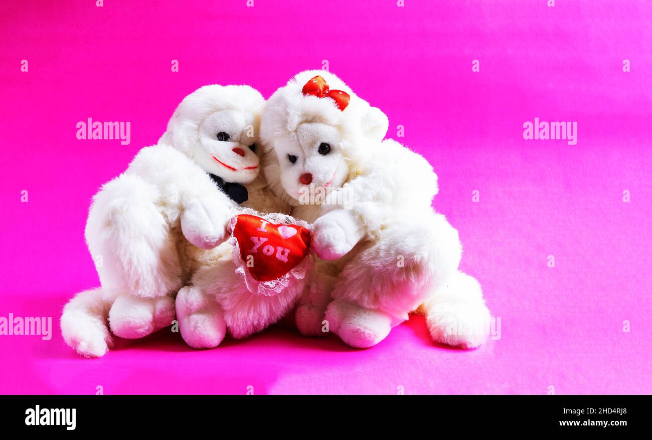 Soft toy monkeys holding a heart on a pink background. A symbol of love. valentine's day. Stock Photo