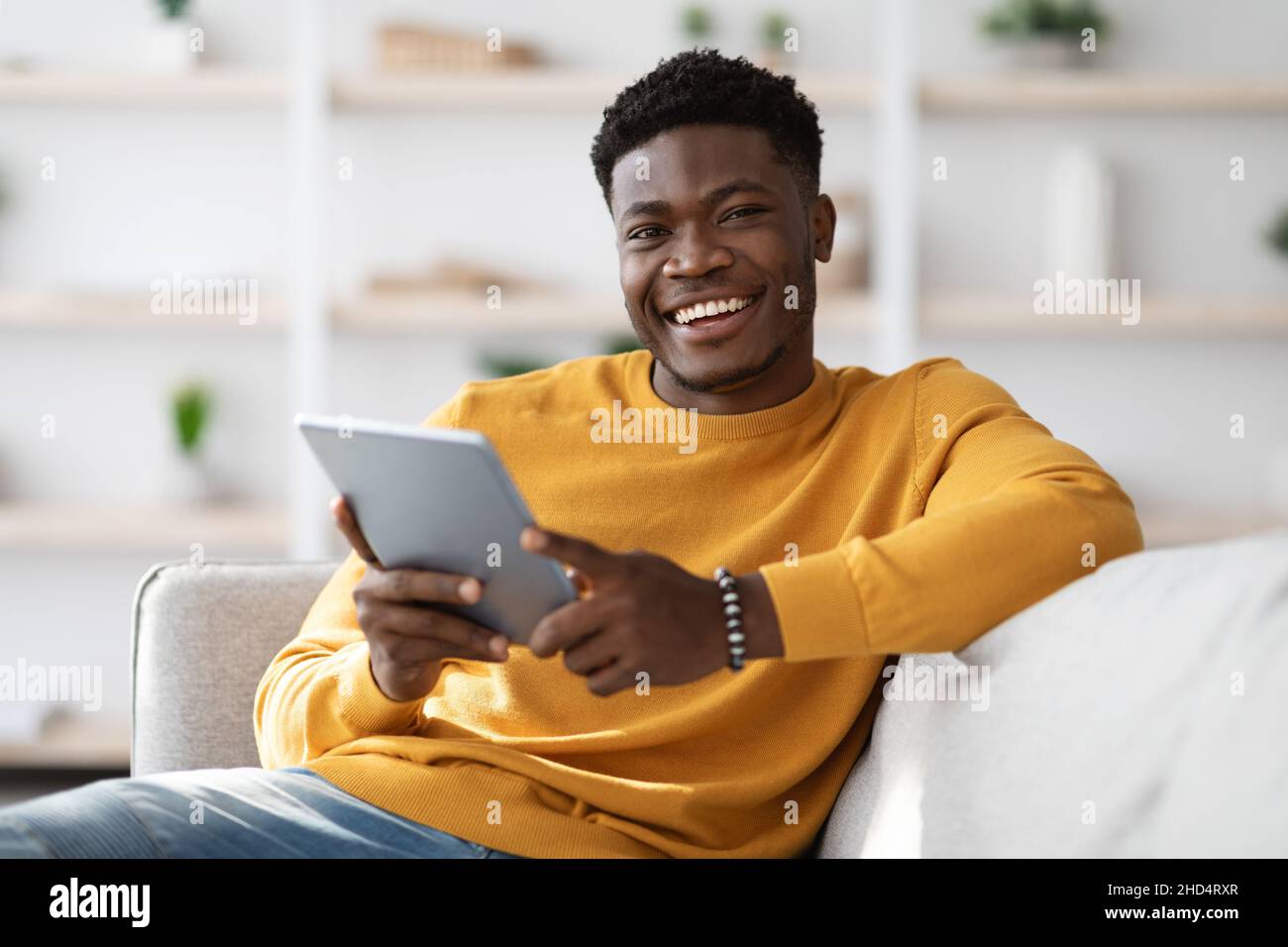 Happy black guy using digital tablet at home Stock Photo