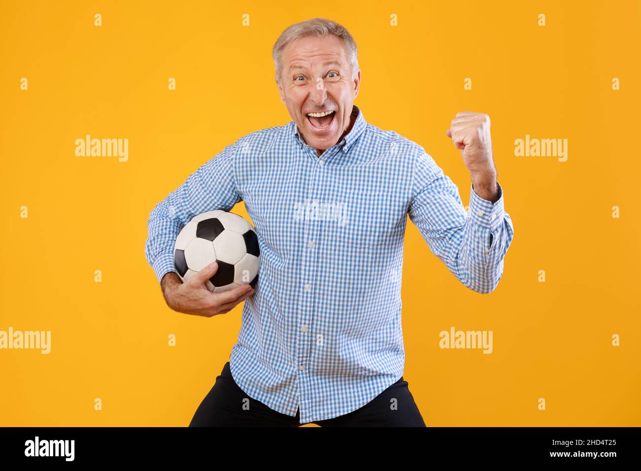 Mature man posing with soccer ball on yellow background Stock Photo - Alamy