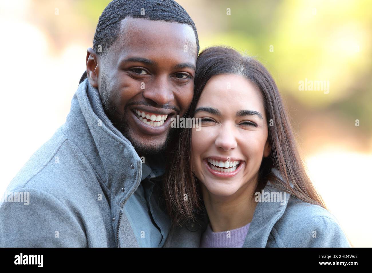Happy interracial couple laughing with white teeth at camera in winter Stock Photo