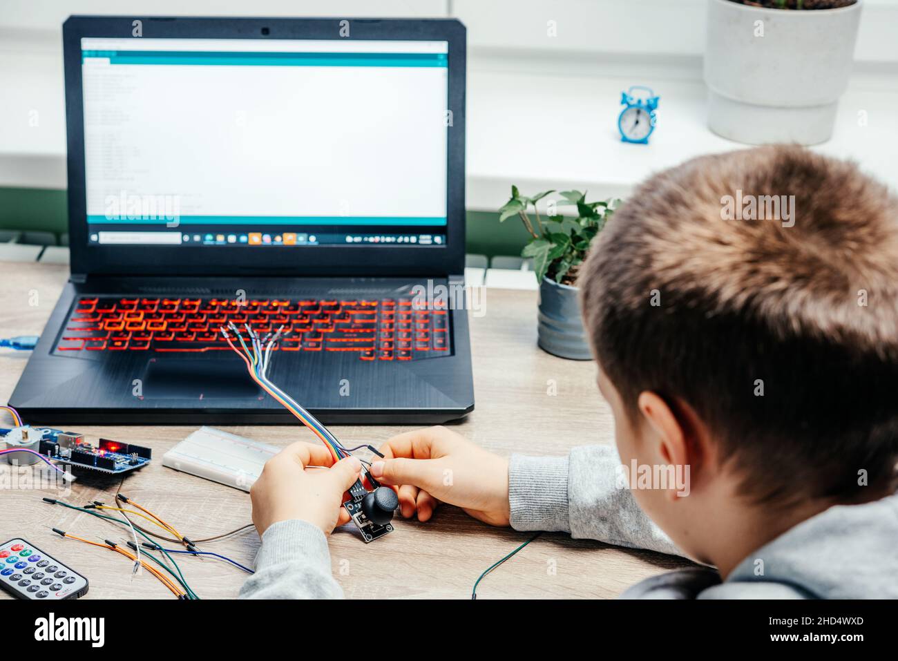 A boy plugging cables to sensor chips while learning arduino coding and ...