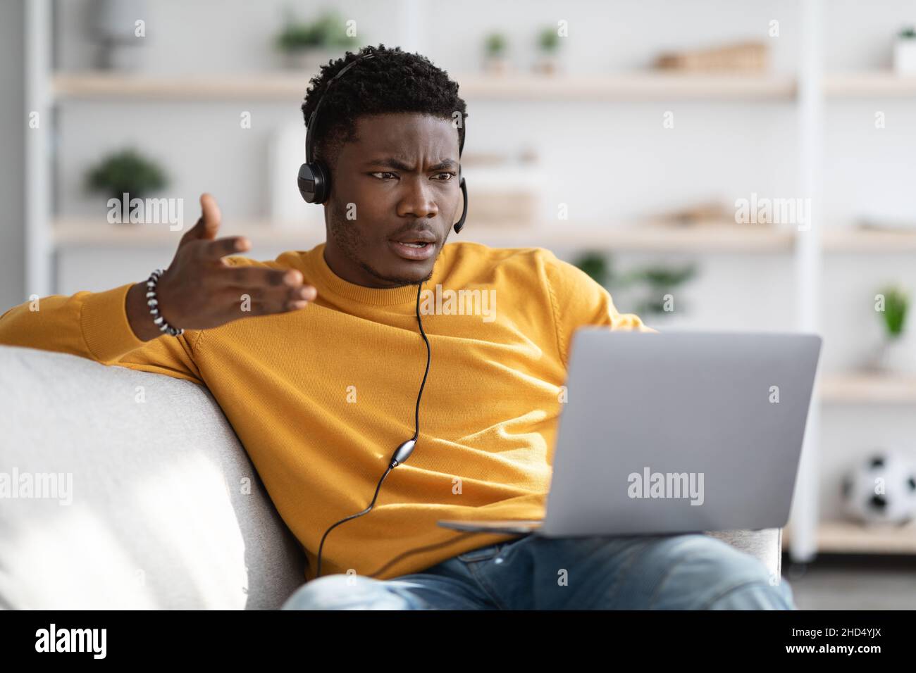 Furious black guy having video call, using laptop at home Stock Photo