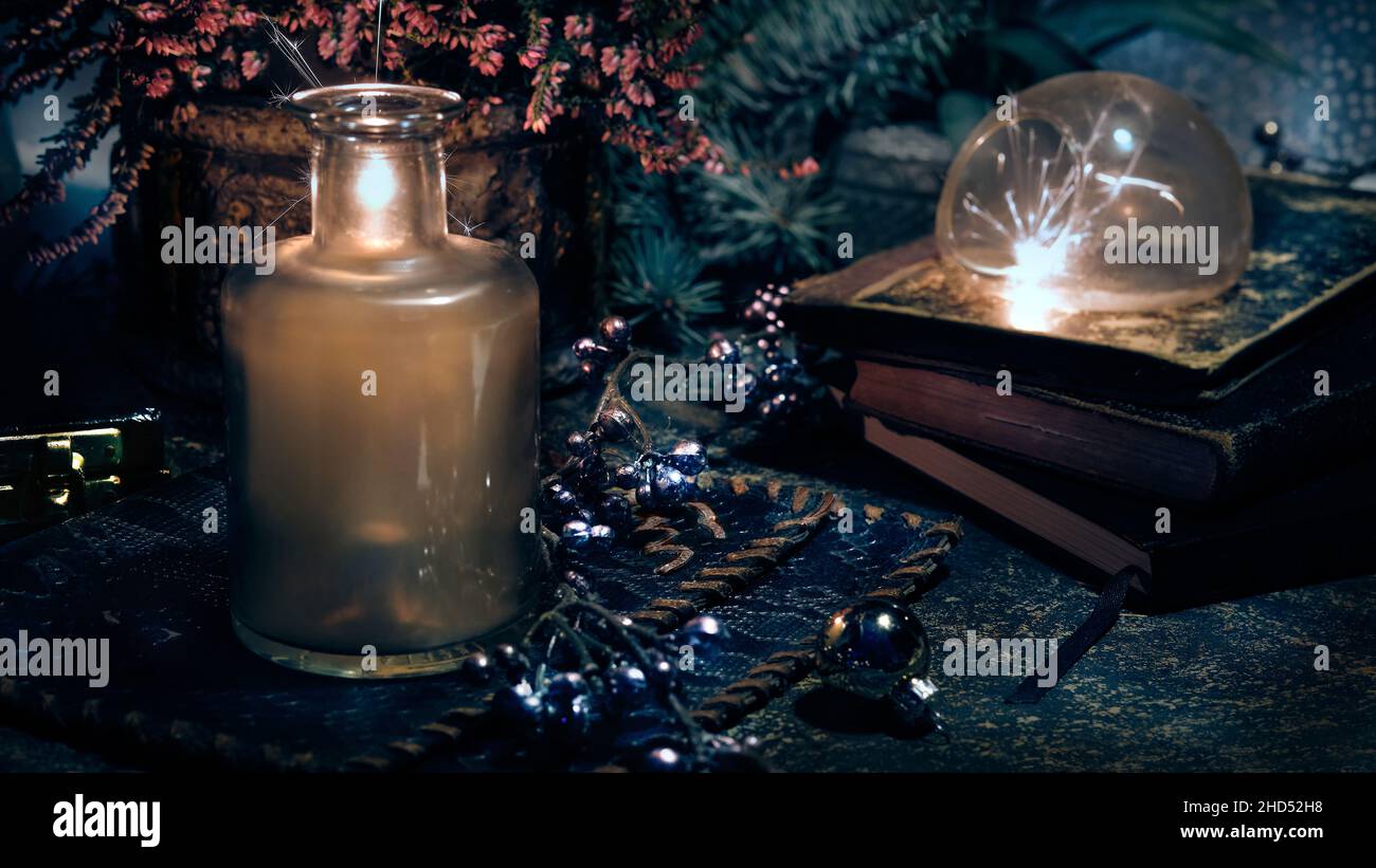 Magic lights with sparkles and orange glow in vintage glass jars. Lights and old books. Fir twigs and heather flowers. Romantic still life. Stock Photo