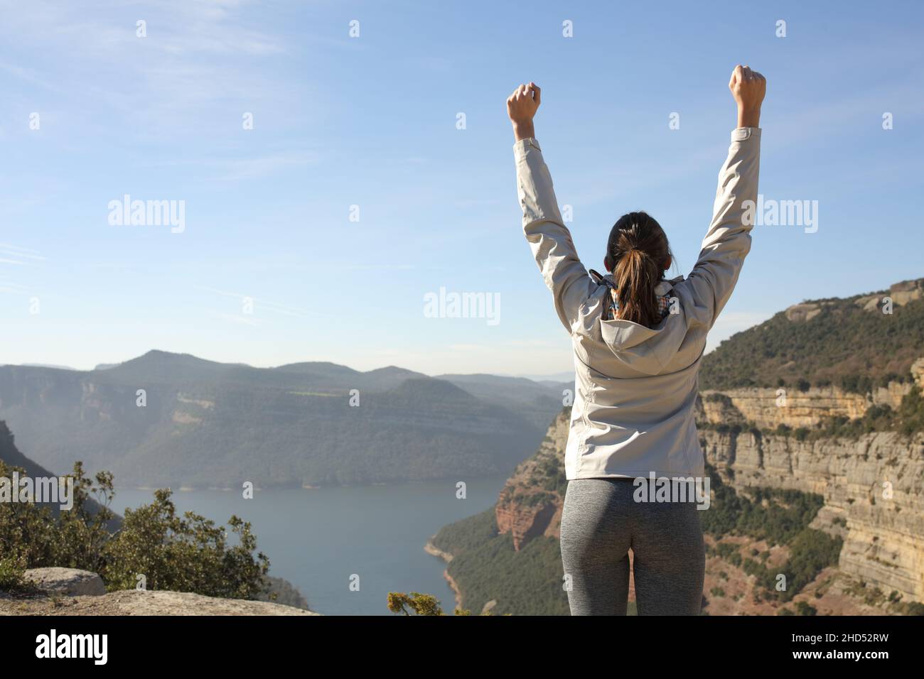 Back view portrait of a happy trekker raising arms in nature celebrating success Stock Photo