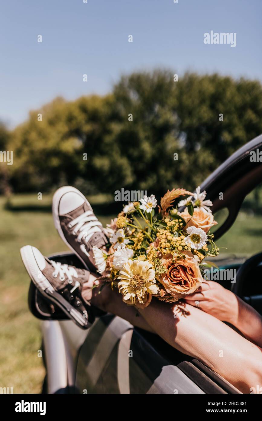 Woman with feet outside of truck window with a bouquet during summer Stock Photo