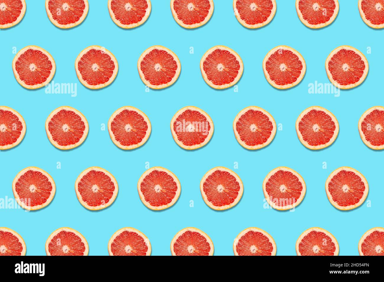 Grapefruit Slices on a Blue Background in a Pattern Stock Photo