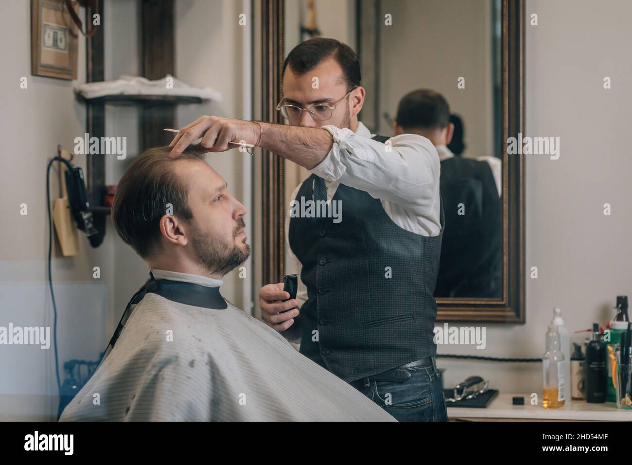View through window, hairdresser barber cuts hair with scissors. Stock Photo