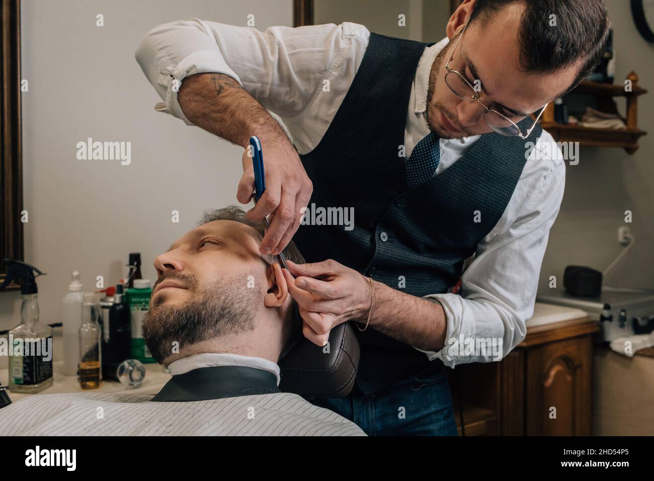 Barber hairdresser cuts facial hair with razor Stock Photo - Alamy